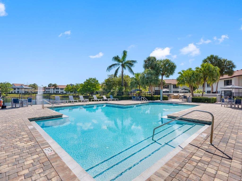 A large outdoor swimming pool surrounded by palm trees.